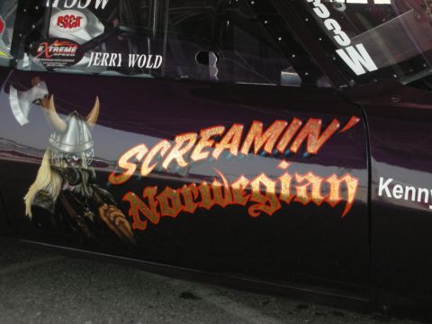 1998 Ford Crown Victoria - A drag racing car features custom artwork and lettering on its side, along with sponsor decals.