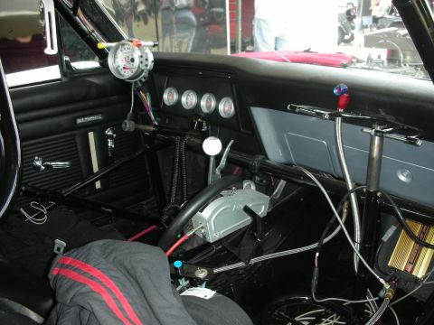 1998 Ford Crown Victoria - The interior of a race car is shown, a tachometer, multiple gauges, a shifter, and a prominent roll cage.