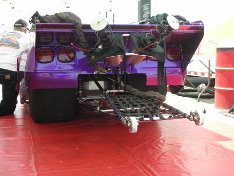 1998 Ford Crown Victoria - A person works on the rear of a custom purple drag racing car.