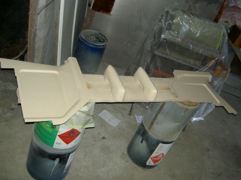 1967 Ford Ranchero - A tan interior trim piece, possibly for a vehicle's cabin, is shown resting on industrial barrels.