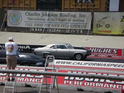 1998 Ford Crown Victoria - A silver classic coupe races down the track next to another vehicle, with a spectator capturing the moment.