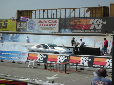 1998 Ford Crown Victoria - A silver drag car performs a burnout, creating smoke on the track at the Auto Club Dragway.