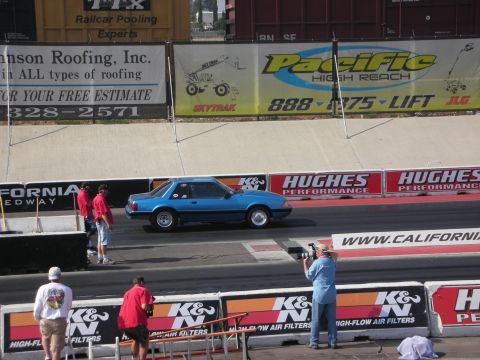 1998 Ford Crown Victoria - Blue coupe on drag strip with spectators and photographers.