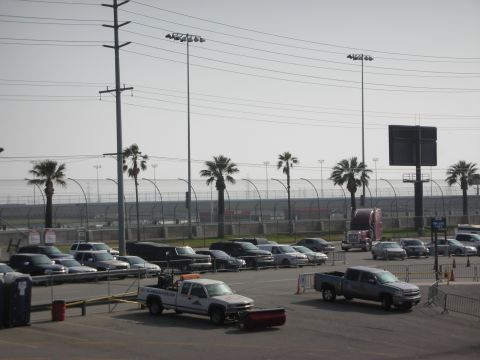 1998 Ford Crown Victoria - A parking lot scene features numerous vehicles, including cars and trucks, with palm trees lining the background.