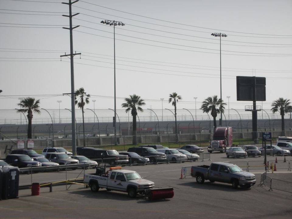 Parking lot scene with various cars, trucks, and palm trees