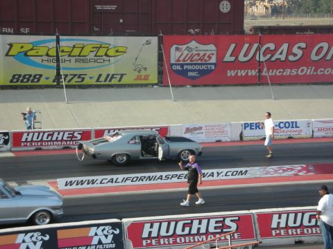 1998 Ford Crown Victoria - Drag racing event with multiple vehicles and spectators under sponsor banners.