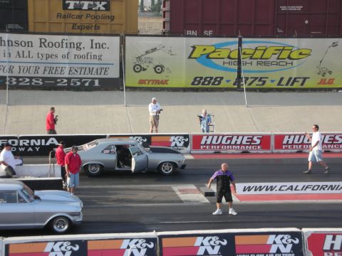 1998 Ford Crown Victoria - Cars and people at a drag racing event with sponsor banners in the background.