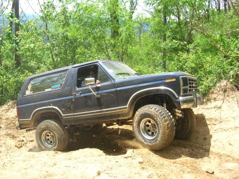 1984 Ford Bronco - This lifted Ford Bronco is navigating a challenging off-road trail.