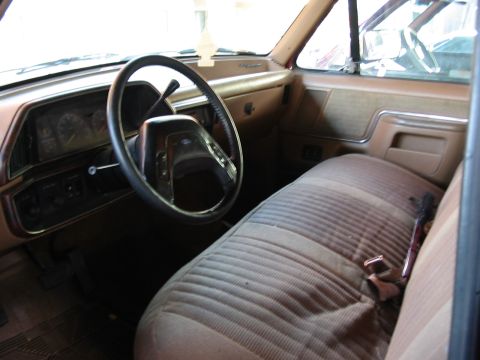 1991 Ford Bronco - The interior of a 1992 Ford F-150 features a striped brown and tan seat and a dark dashboard.