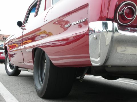 1998 Ford Crown Victoria - A red classic car, possibly a Bel Air, is shown from a low angle, highlighting its wide drag radial tire and chrome bumper.
