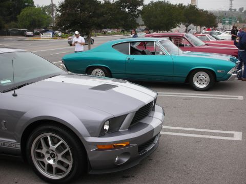 1998 Ford Crown Victoria - Several cars are parked in a lot, including a modern Mustang and classic Chevelle.