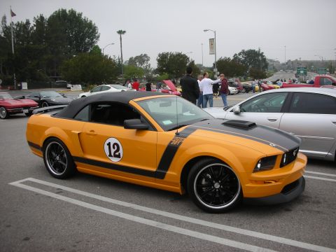 1998 Ford Crown Victoria - A bright orange convertible Mustang, identified as a Boss 302, is parked at an outdoor event.