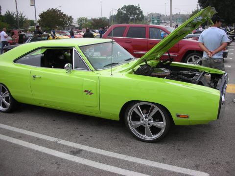 1998 Ford Crown Victoria - A lime green 1970 Dodge Charger R/T is parked with its hood open, displaying custom wheels and modifications.