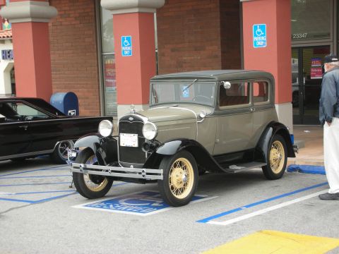 1998 Ford Crown Victoria - A classic 1929 Ford Model A sedan is parked in a handicapped spot.