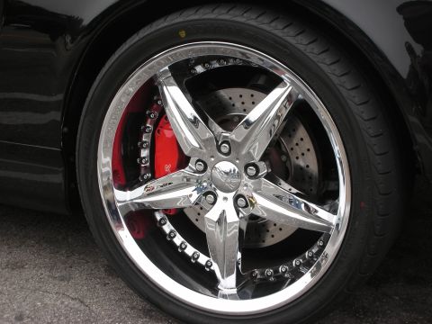 1998 Ford Crown Victoria - Close-up of a custom chrome wheel and tire assembly on a black vehicle.