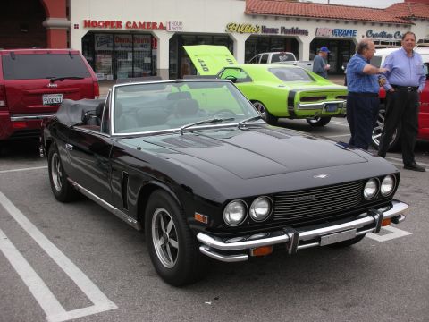 1998 Ford Crown Victoria - A black convertible sports car is parked in a lot next to other vehicles.
