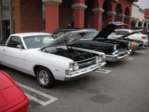 1998 Ford Crown Victoria - A line of classic cars, including a white Ford Ranchero and a black Chevrolet, are parked with their hoods open.