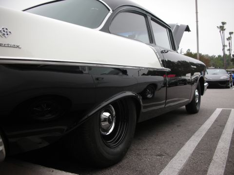 1998 Ford Crown Victoria - A classic two-tone Chevrolet is parked in a lot, with a modern sports car visible in the background.