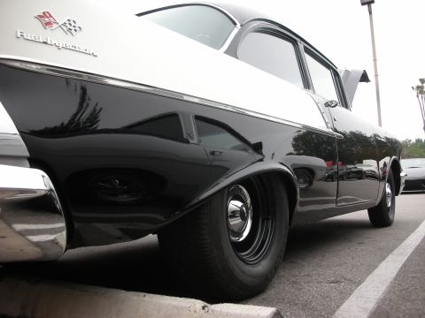 1998 Ford Crown Victoria - A two-tone black and white 1955 Chevrolet Bel Air is parked at a car meet, with another car visible in the background.