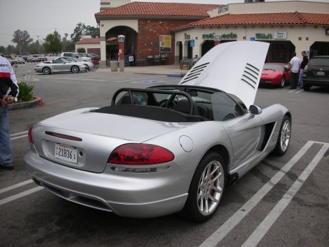 1998 Ford Crown Victoria - A silver convertible with its hood up is parked in a lot next to other vehicles.