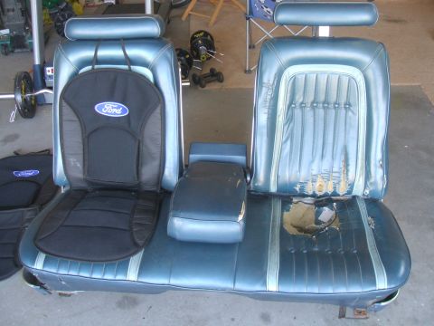 1974 Ford Ranchero - Two blue vinyl car seats, one with a Ford logo cover, sit next to a center console.
