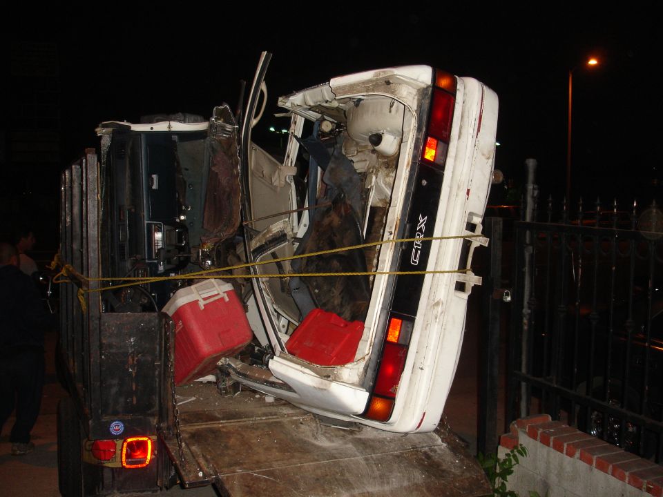 Car on trailer, upside down. CRX badge visible on rear