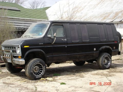 1979 Ford Bronco - A black van with tinted windows and off-road tires sits on a dirt lot.