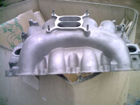 1964 Ford 427 - Aluminum intake manifold with dual carburetor openings, sitting in a cardboard box.