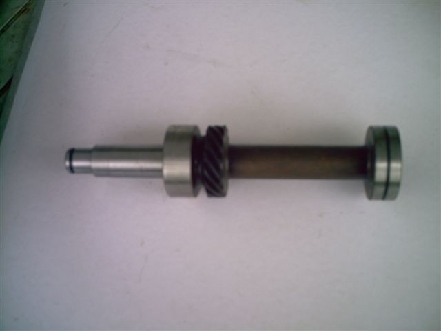 Metal shaft with two bearings and a helical gear, against a white background