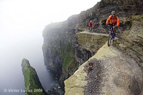 1968 Ford Mustang - Cyclists navigate a precarious cliffside trail with dramatic ocean views.