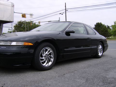 1996 Mercury Grand Marquis - Side view of a black coupe with custom chrome wheels. The 'LINCOLN' badge is visible on the front fender.