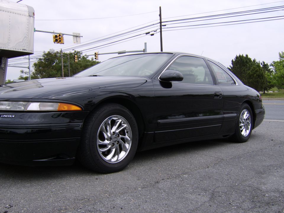 Black Lincoln Mark VIII coupe with chrome swirl wheels, low front three-quarter view