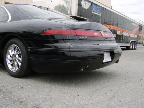 1996 Mercury Grand Marquis - Black Lincoln Mark VIII parked next to a Harley-Davidson racing trailer.
