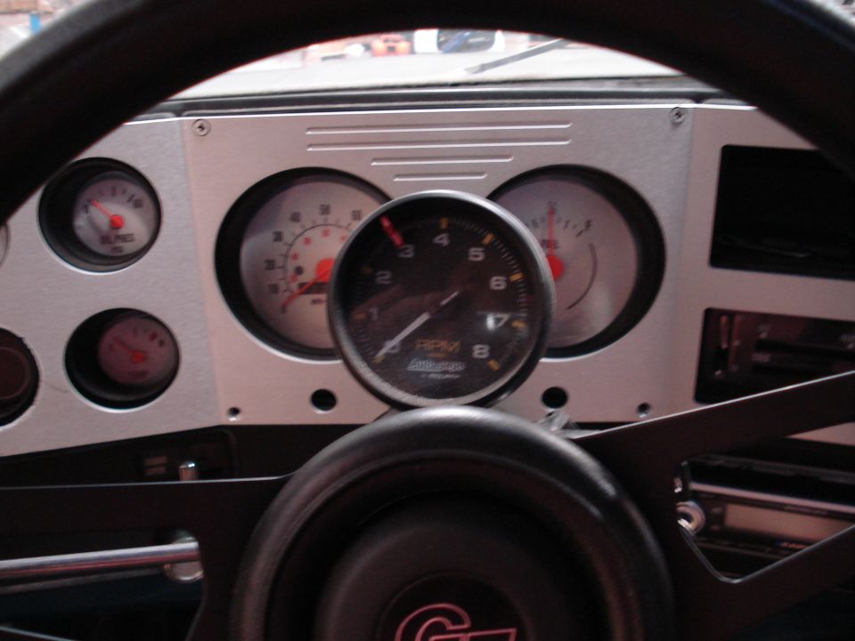 Dashboard interior with tachometer, speedometer, oil pressure, and temperature gauges. Aftermarket gauges are installed