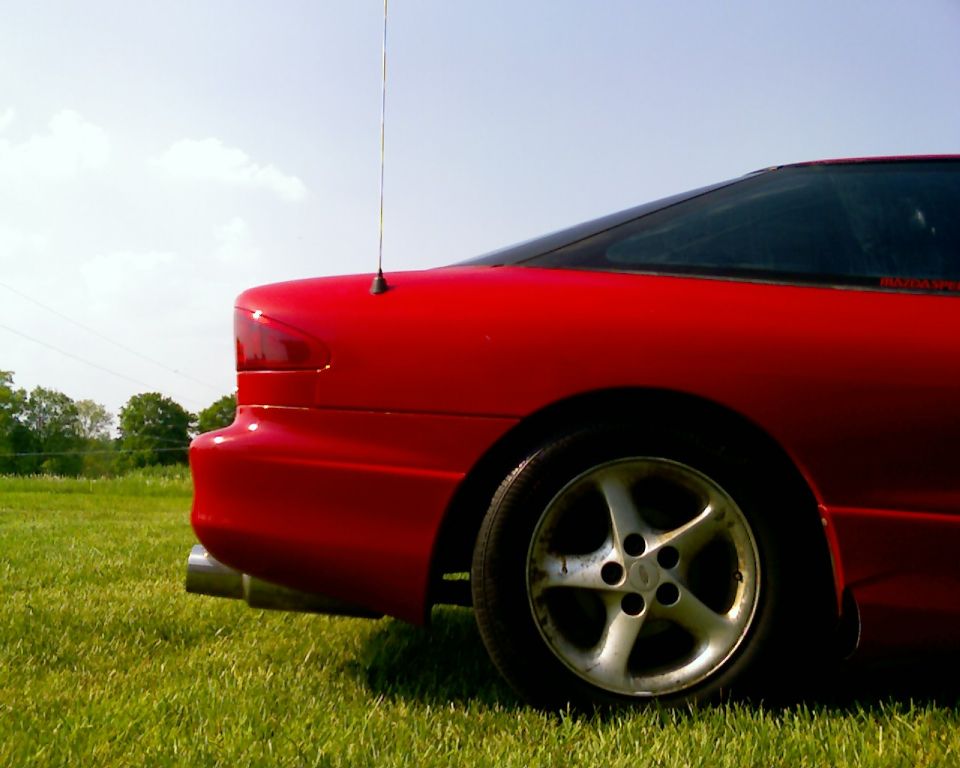Red 1993 Ford Probe rear quarter panel and wheel, parked on grass