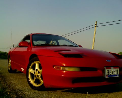 1993 Ford Probe - A red 1993 Ford Probe GT is shown from a 3/4 front view, gold five-spoke wheels and a clear blue sky.