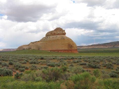 1997 Ford Ranger - A vast desert landscape features a prominent, layered rock formation under a dramatic sky.