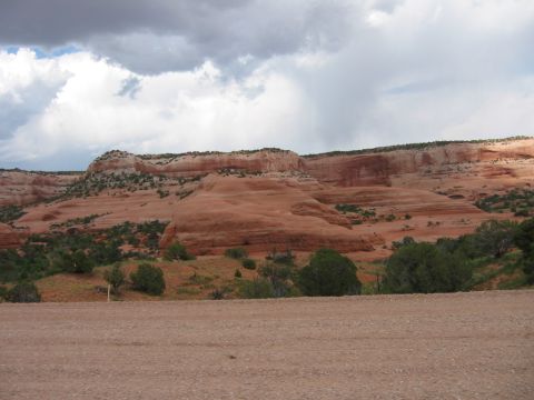 1997 Ford Ranger - A scenic view of desert rock formations under a dramatic cloudy sky, with a dirt road in the foreground.