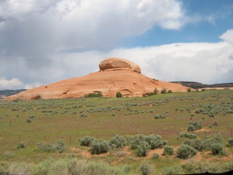 1997 Ford Ranger - Desert landscape with a prominent rock formation and sparse vegetation under a dramatic sky.