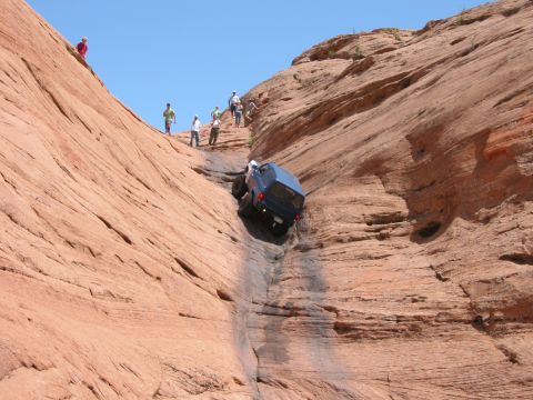1997 Ford Ranger - A blue off-road vehicle navigates a challenging descent down a narrow, rocky canyon with spectators watching from above.