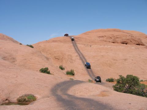 1997 Ford Ranger - Multiple off-road vehicles navigate a challenging dirt path in a desert environment. Supermotors.net logo visible.