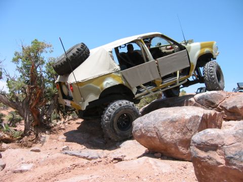 1997 Ford Ranger - A heavily modified off-road vehicle navigates a rocky terrain under a clear blue sky.