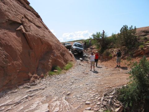 1997 Ford Ranger - Off-road vehicles traverse a challenging rocky path under a clear blue sky with scattered clouds.