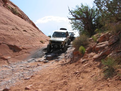 1997 Ford Ranger - Off-road vehicles driving on a challenging rocky trail with red rock formations.