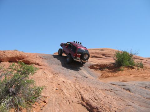 1997 Ford Ranger - A red SUV navigates a challenging off-road course on a sunny day.