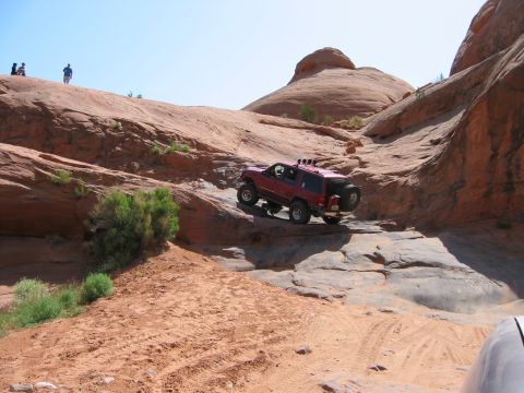 1997 Ford Ranger - A red 1997 Ford Ranger navigates a challenging rocky terrain in a desert landscape.