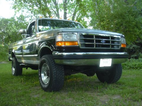 1992 Ford F-250 - This two-tone 1992 Ford F-250 pickup truck is shown in a front 3/4 view, parked on grass with trees in the background.