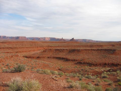 1997 Ford Ranger - A vast desert scene unfolds with layered red rock formations and sparse vegetation under a partly cloudy sky.
