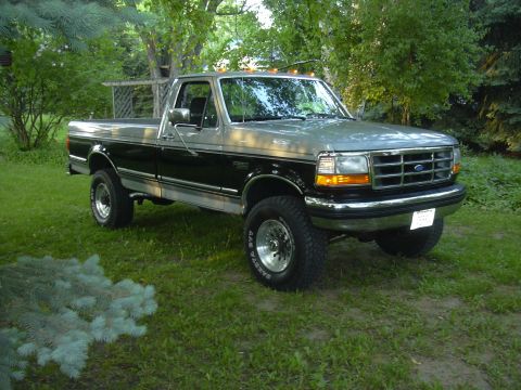 1992 Ford F-250 - This two-tone 1992 Ford F-250 pickup truck is shown from a three-quarter front view, parked on a grassy lawn.