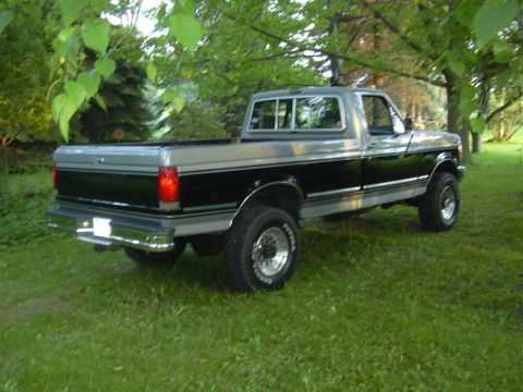 1992 Ford F-250 - This two-tone pickup truck is seen from the rear 3/4 angle, parked on a grassy lawn.